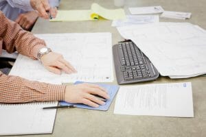 accountants analyzing data sheets on a tan table in an office