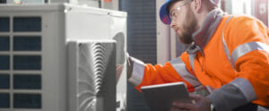 air conditioning engineer with in an orange safety jacket and construction helmet