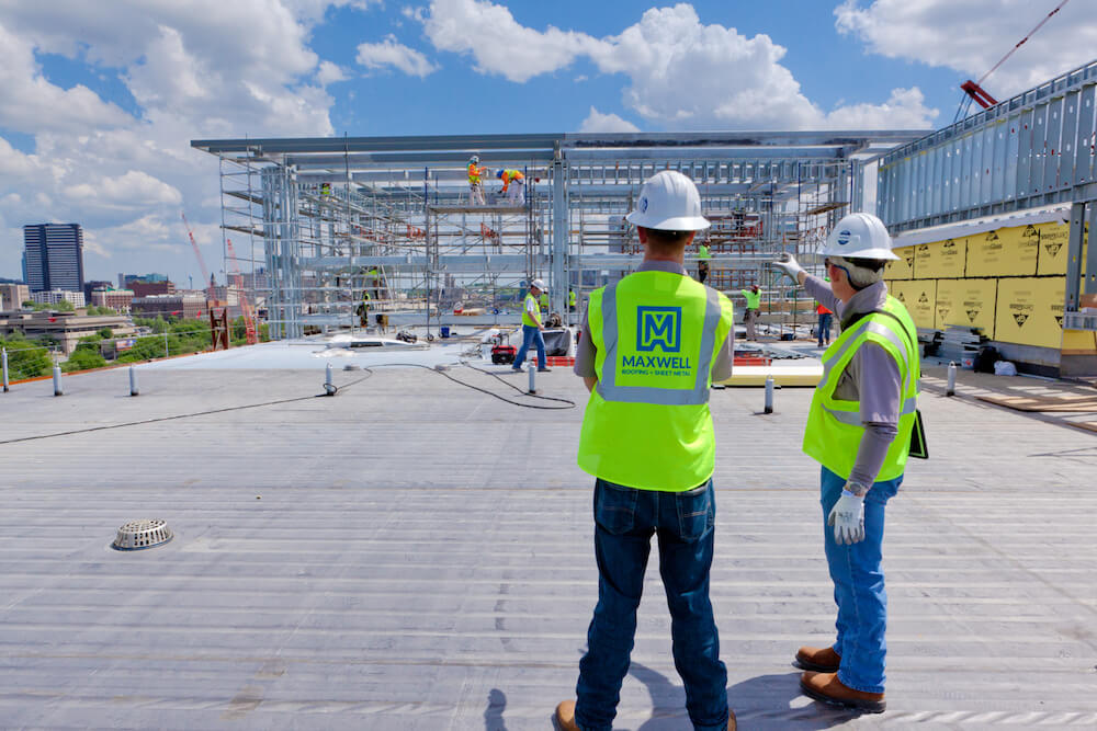 two maxwell engineers analyzing construction site on a sunny day with white clouds on a rooftop