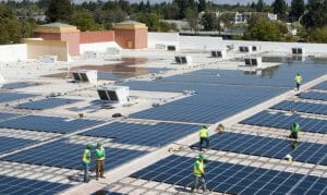 workers installing solar panels on a commercial roof