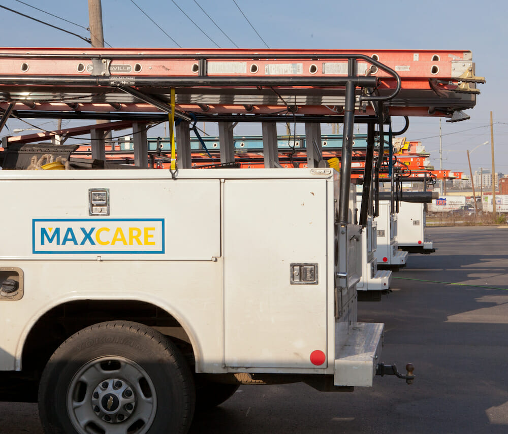 Maxwell roofing service trucks parked in a row in a parking lot with logo on the side