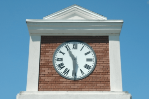 White clock tower white brick displaying 11:30 with clear blue skies in the background