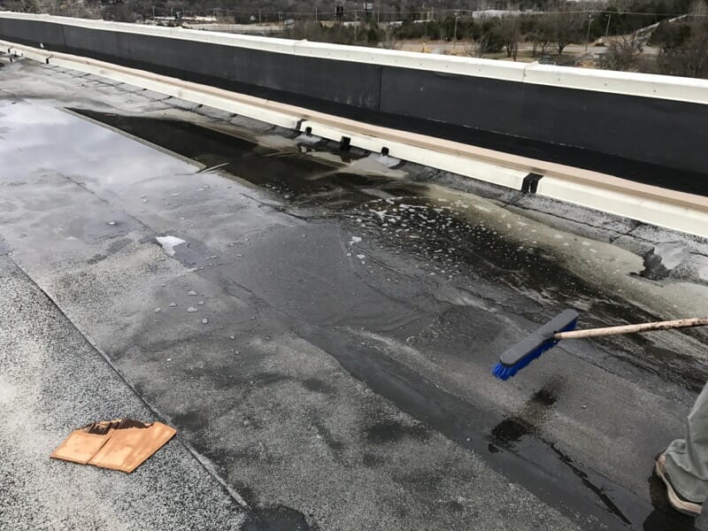 black debris and water from commercial roof with a broom