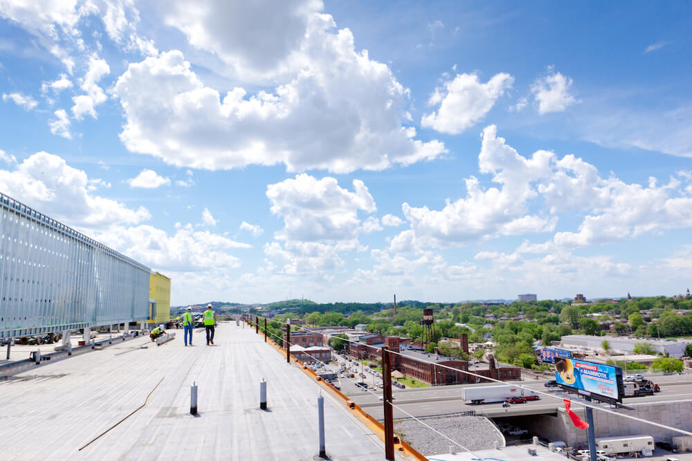 two roofers walking away on a commercial roof looking over The Factory in Franklin, Tennessee