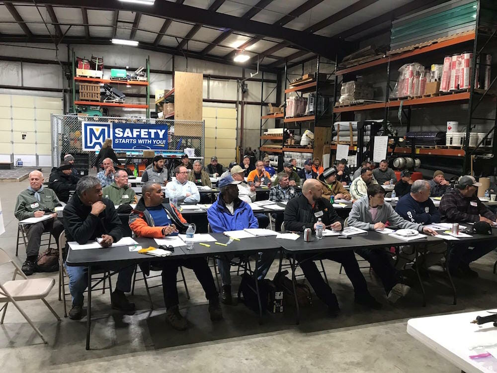 people sitting in a large factory setting sitting at tables in attendance of a CERTA event, CERTA Train-the-Trainer Certification