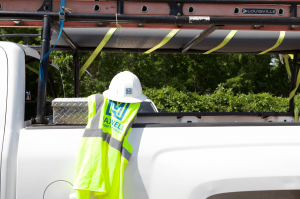 maxwell roofing safety vest and helmet draped over white service truck