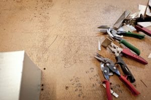 pliers and and wrenches on a brown work table with handwriting