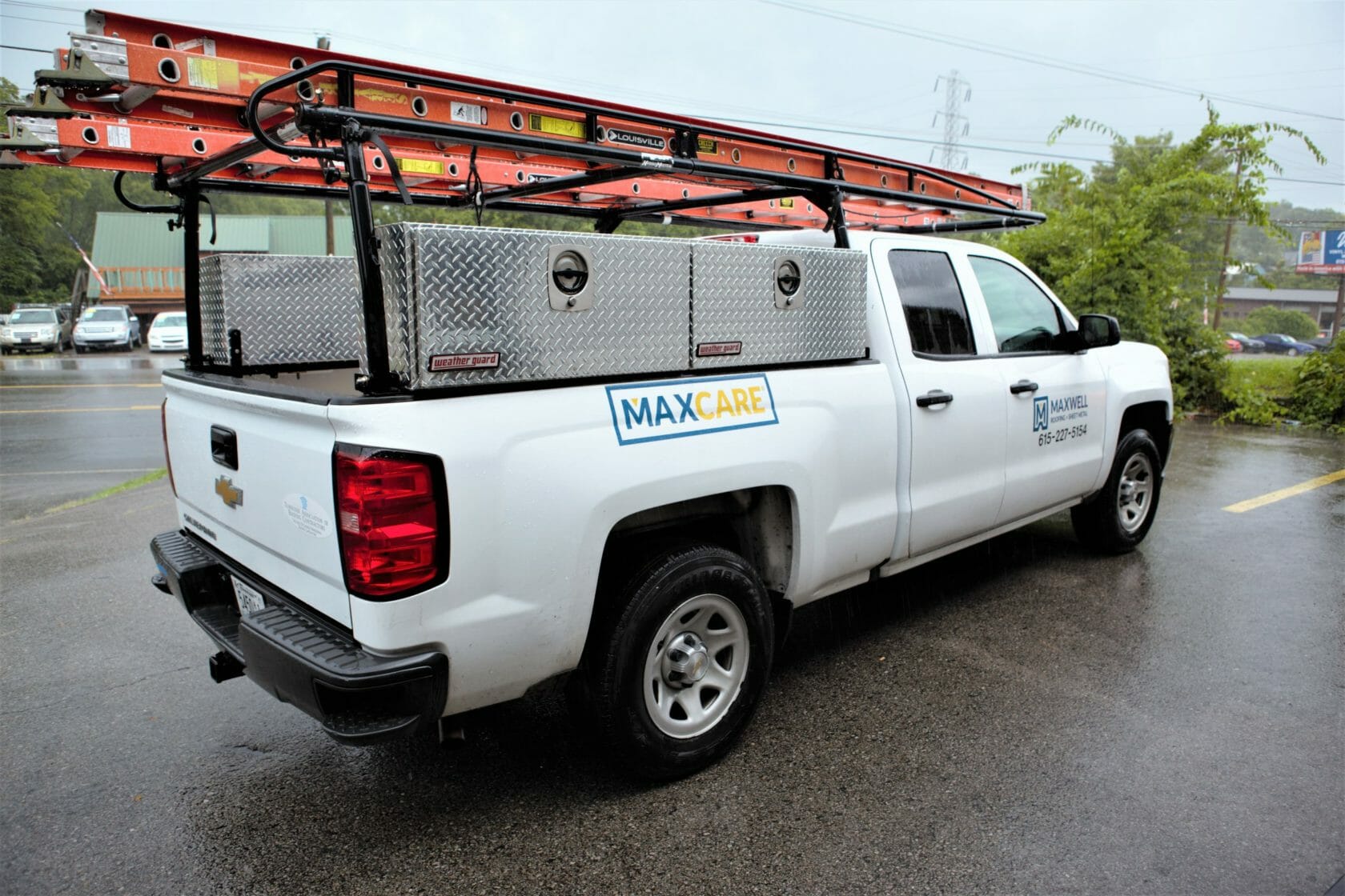 side profile of maxwell roofing service truck in a parking lot