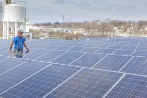Worker walking through solar panels on a roof