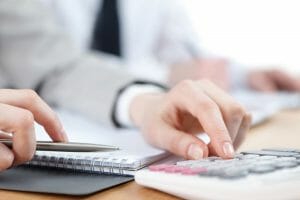 person using calculator and taking notes on notebook