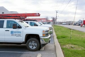 several Maxwell Roofing service trucks parked in a parking lot