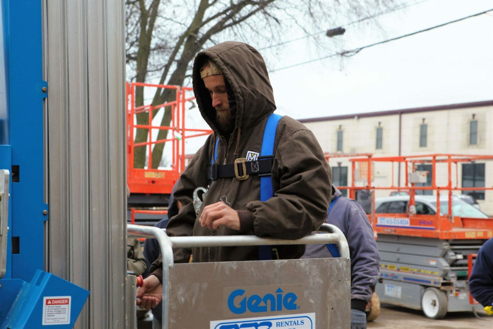 worker with a hooded jacket in a lift working on a roof safely