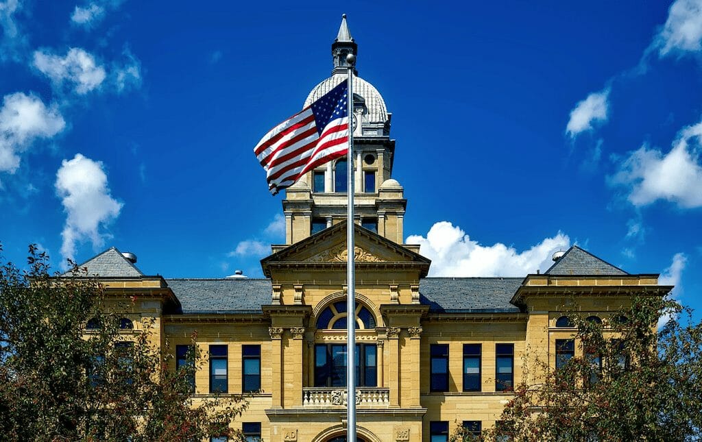 courthouse with an american flag waving in front of it.