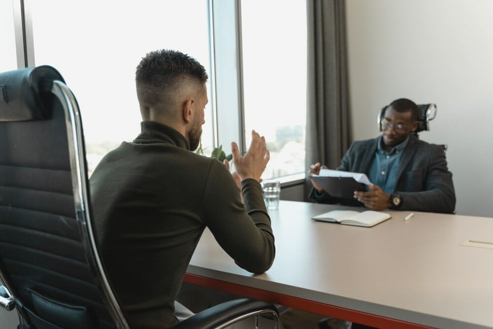 2 business men talking at desk