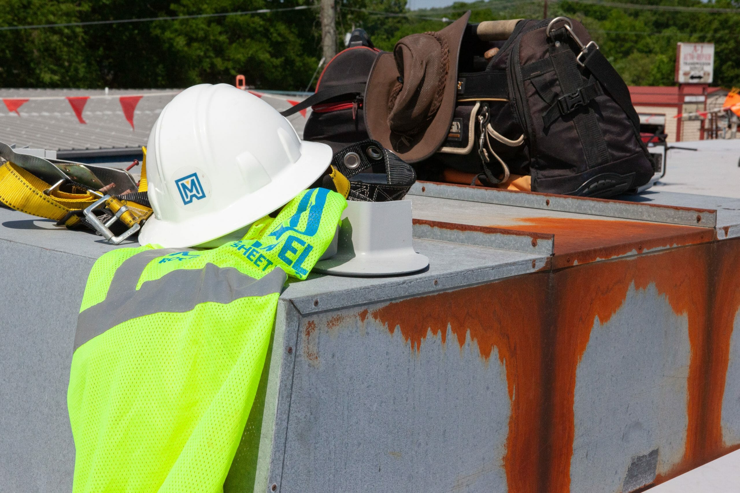 Maxwell roofing hat and construction vest on a job site.