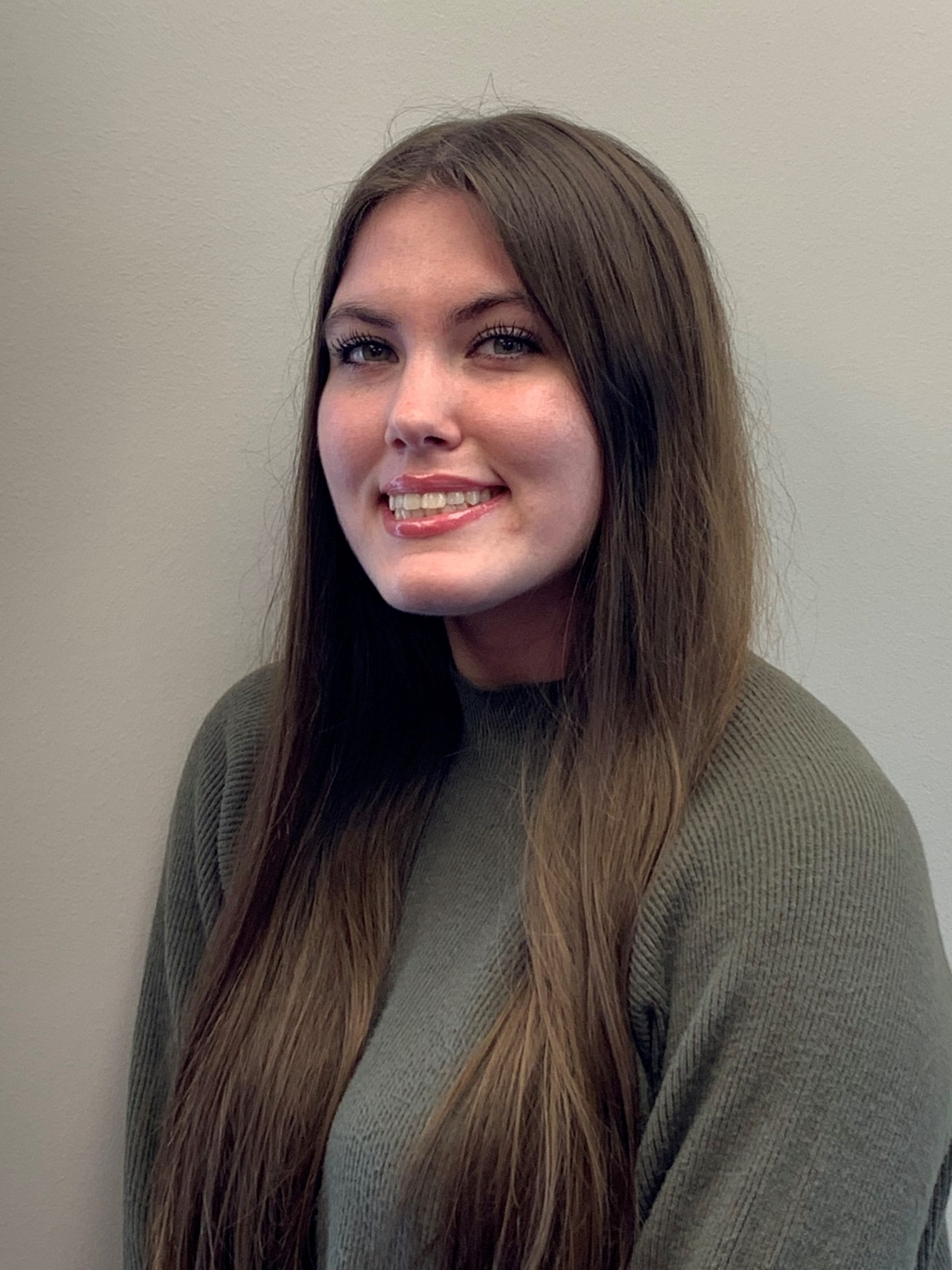 Britney Conway in a professional portrait, smiling, wearing a green sweater.