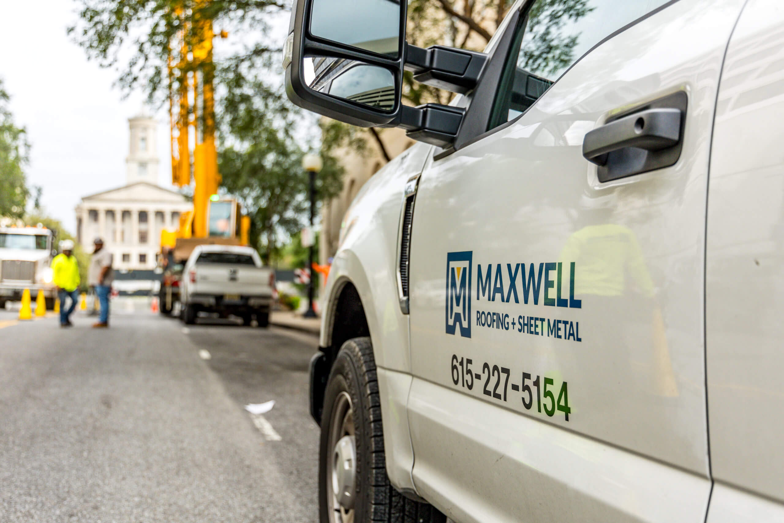 maxwell roofing truck driving on a city street