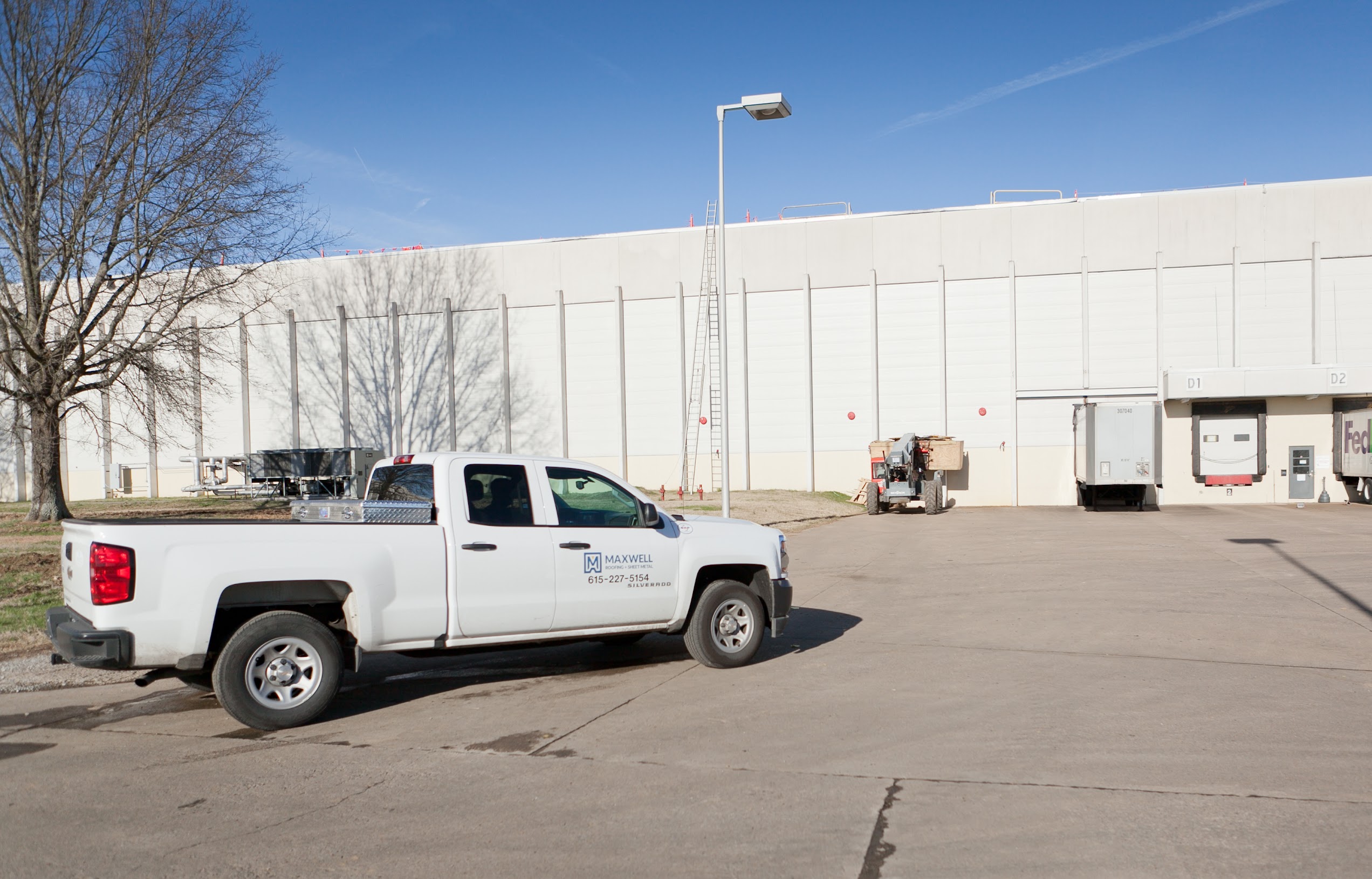 white maxwell roofing pickup truck in an empty lot