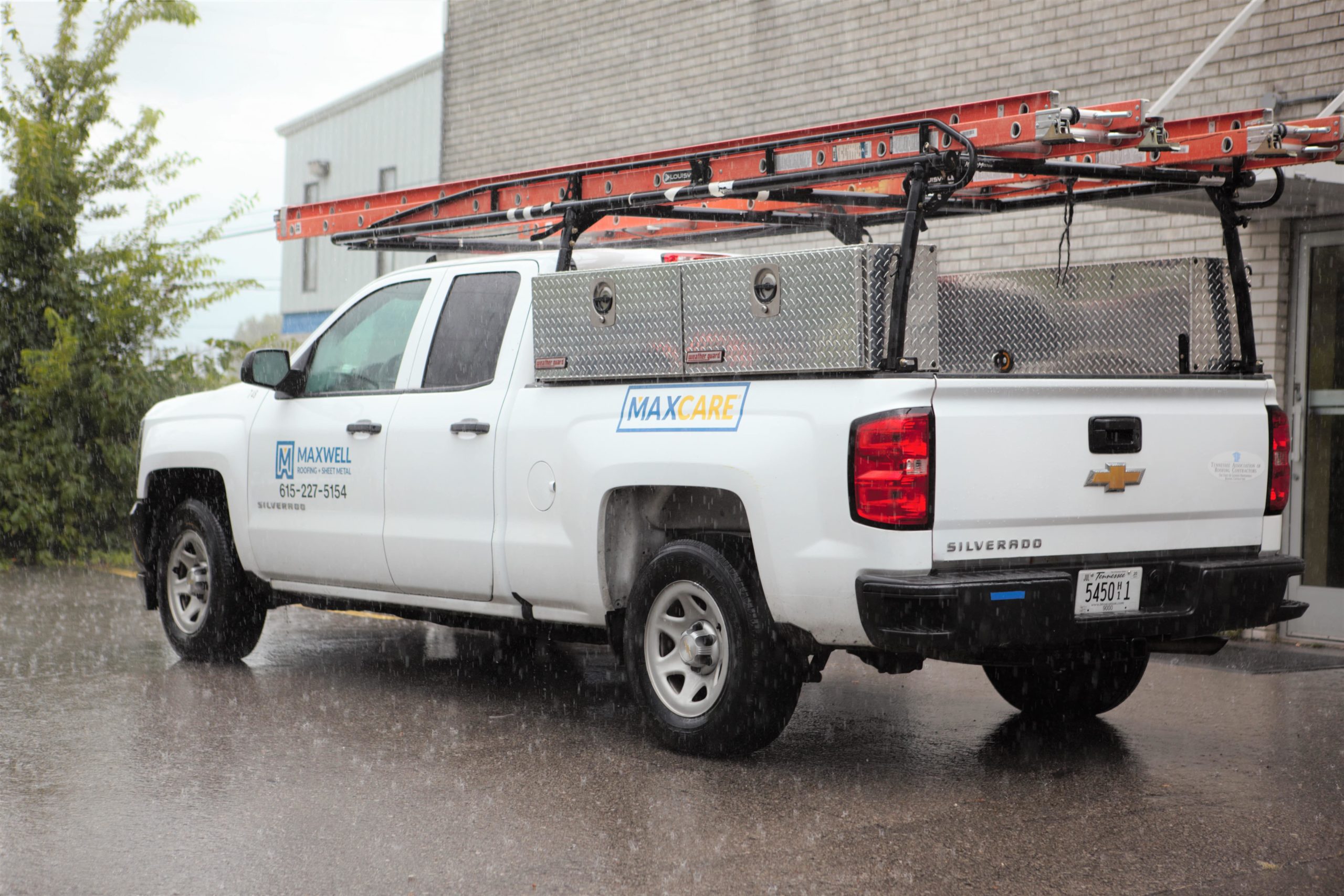 maxwell roofing truck at a commercial roofing job site in the rain